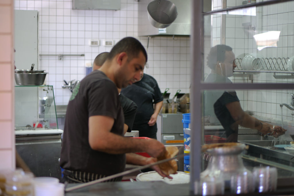 Abu Hasan Küche. Vier Person mit schwarzen T-Shirts kochen. Tel Aviv.