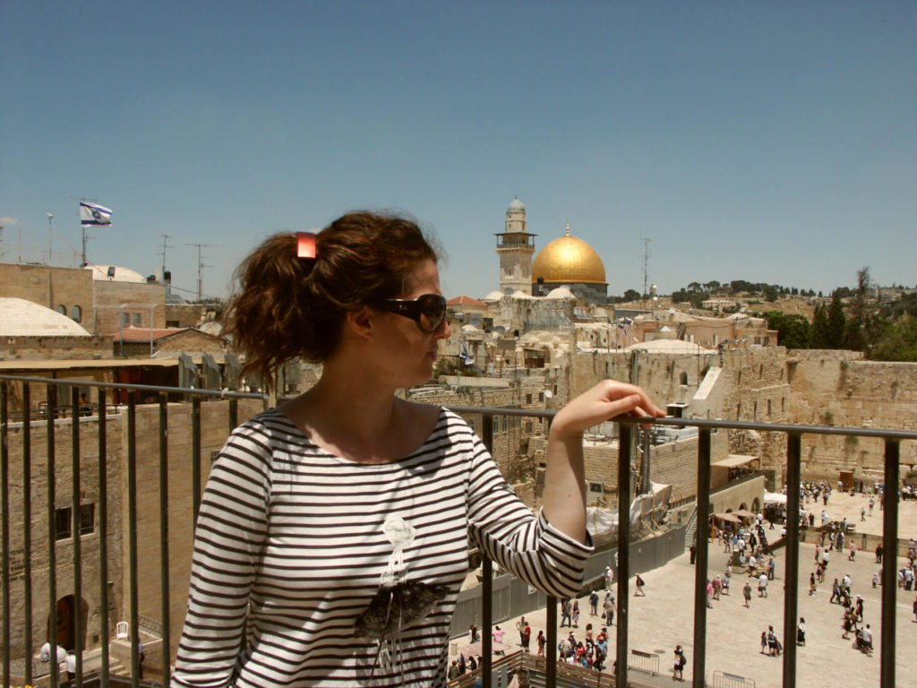 Eine braunhaarige Frau mit gestreiftem T-Shirt blinkt hinunter auf die Klagemauer in Jerusalem. Israel.