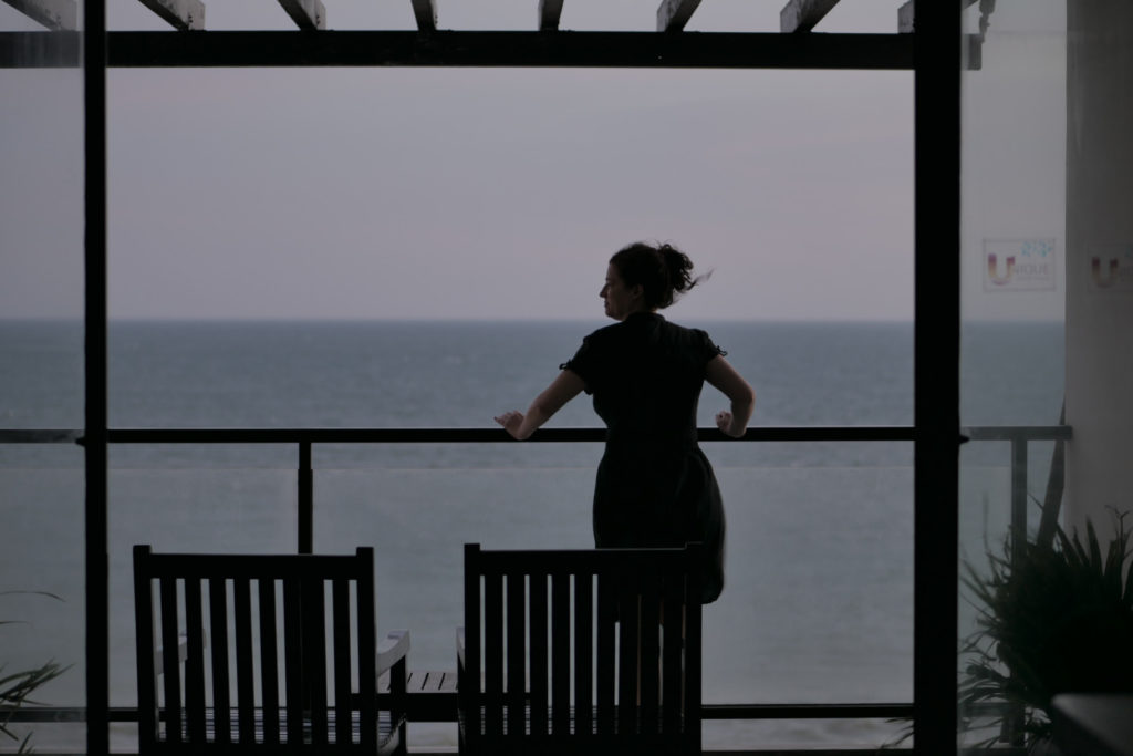 Unique Mui Ne Hotel. Eine Frau steht auf dem Balkon und sieht sich das Meer an. Vietnam.