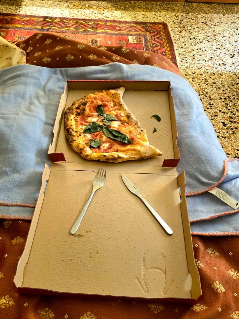 Pizza Calzone von Rossopomodoro im Karton auf dem Bett in Casa Villa Gardenia