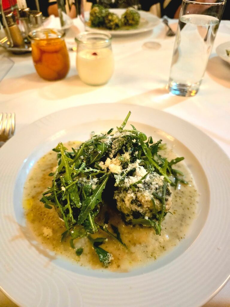 Spinatknödel an Kräuterrahmsauce mit Rucola garniert